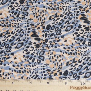 May include: Blue, beige, and black animal print fabric with a repeating pattern. The fabric is measured with a ruler in inches.
