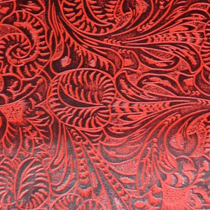 May include: Red embossed leather with a floral pattern. The leather has a textured, raised design.