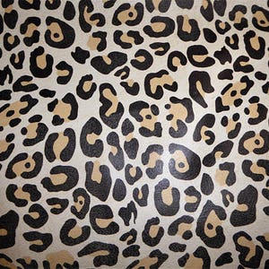 May include: A seamless pattern of black and tan leopard spots on a white background.