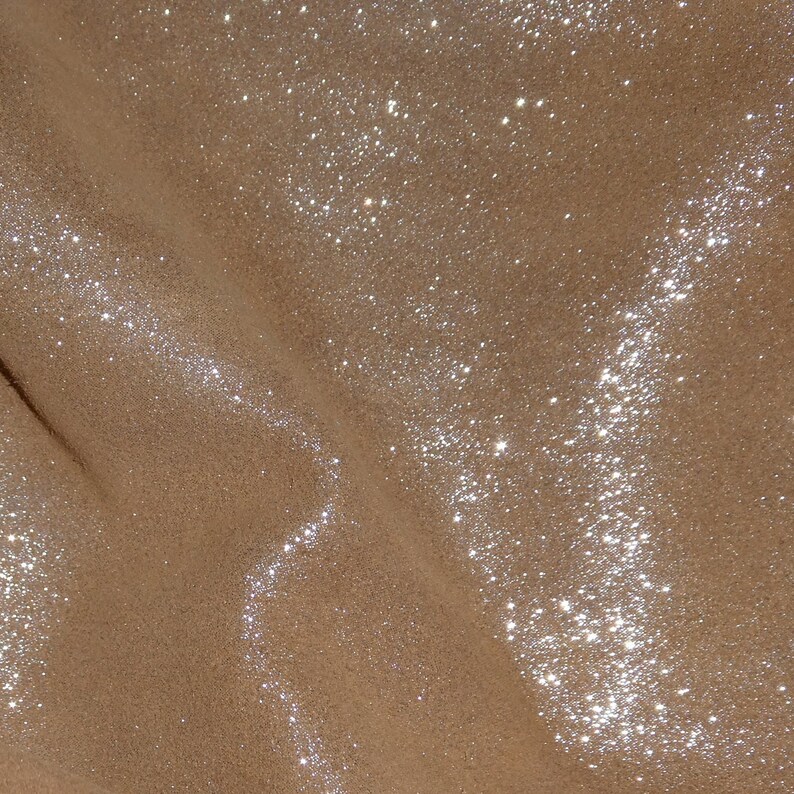 Puede incluir: Primer plano de una tela marr&oacute;n con textura brillante. La tela tiene un brillo sutil y est&aacute; cubierta de peque&ntilde;as part&iacute;culas brillantes.
