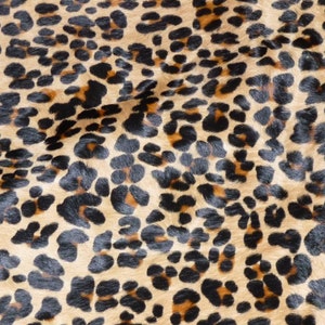 May include: Close-up of a leopard print pattern. The design features black and brown spots on a tan background. The pattern is a repeating design, with the spots varying in size and shape.