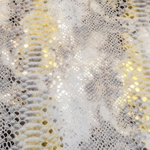 May include: A close-up of a fabric with a snakeskin pattern in shades of grey and gold.