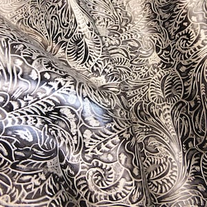 May include: Black leather with a white embossed floral pattern. The leather is textured and has a slight sheen.