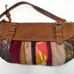 May include: A brown leather shoulder bag with a flap closure and a patchwork design. The bag features a variety of colors, including burgundy, gold, and floral patterns. The strap is also brown leather.