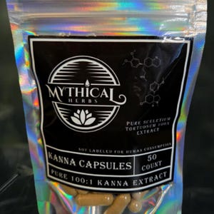 以下が含まれることがあります： カンナカプセルが入ったホログラフィックポーチ。黒いラベルには「Mythical Herbs」と「Kanna Capsules」と書かれています。ラベルには「Pure Sceletium Tortuosum 100X Extract」と「Pure 100:1 Kanna Extract」とも書かれています。ポーチには50カプセルが入っています。