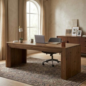May include: A rectangular wooden desk with a natural grain finish, featuring a thick slab-style frame. The desk surface holds a silver laptop, a white ceramic mug, a small potted succulent, a brass desk lamp, and a brown leather pencil cup.