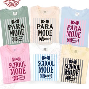 May include: Six folded t-shirts in pastel shades, each with a unique graphic. The designs include a bow tie, vertical stripes, and the text "PARA MODE OFF" or "SCHOOL MODE OFF". The shirts are neatly arranged for display.