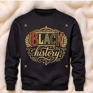 Może przedstawiać: Czarna bluza z napisem "BLACK history" w dekoracyjnym wzorze. Tekst jest w kolorze czerwonym, żółtym i zielonym, ze złotymi akcentami. Bluza ma okrągły dekolt i długie rękawy.
