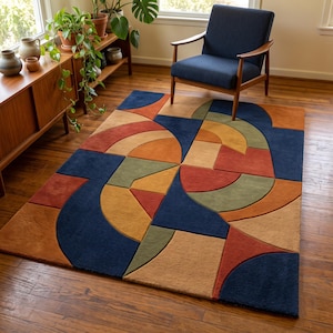 May include: A rectangular area rug featuring a geometric pattern of interlocking shapes in navy blue, burnt orange, mustard yellow, and sage green. The design consists of semicircles, triangles, and squares arranged in a repeating, abstract composition.