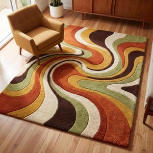 Op de afbeelding: Een retro vloerkleed met een wervelend patroon in tinten oranje, bruin, geel, groen en crème. Het vloerkleed is rechthoekig en ligt op een houten vloer. Een mosterdkleurige fauteuil staat in de buurt.