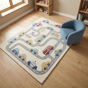 May include: A cream-colored children's rug with a road design and colorful car illustrations. The rug features a gray road pattern with various vehicles, including a police car, fire truck, and other cars. A blue armchair sits nearby.