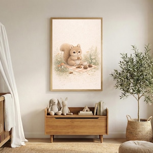Puede incluir: Una impresión enmarcada con una ilustración en acuarela de una ardilla haciendo un picnic. La obra de arte tiene una paleta de colores suaves y pastel y está ambientada en una guardería. La ardilla sostiene una nuez, con una taza y piñas cerca.