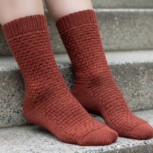 Puede incluir: Un par de calcetines de punto color óxido con un patrón texturizado. Los calcetines son hasta la rodilla y tienen un puño acanalado. Los calcetines están hechos de un material suave y cálido, ideal para el frío.
