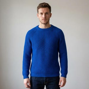 Puede incluir: Un suéter azul brillante con cuello redondo y textura de punto acanalado. El suéter de manga larga está hecho de un material suave y es adecuado para ropa casual. El modelo lleva vaqueros azul oscuro.