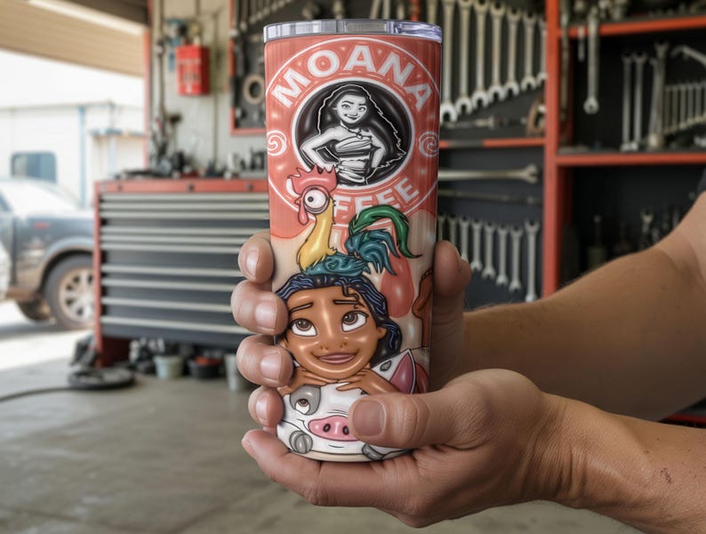 K&ouml;nnte beinhalten: Ein Edelstahlbecher mit einem Cartoon-Design. Der Becher zeigt den Text "MOANA COFFEE" und Illustrationen von Moana und anderen Charakteren auf rotem Hintergrund. Der Becher wird von einer Person in den H&auml;nden gehalten.