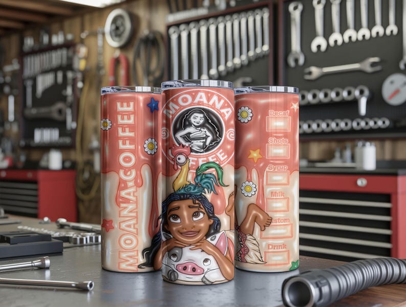 K&ouml;nnte beinhalten: Drei korallenfarbene Edelstahlbecher mit Moana-Motiv, mit der Figur Hei Hei und Pua. Auf einem Becher steht "Moana Coffee" mit einem tropfenden Design. Der andere hat ein Kaffeerezept. Die Becher stehen auf einer Metalloberfl&auml;che.