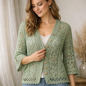 Könnte beinhalten: Hellgrüne Häkeljacke mit V-Ausschnitt und Dreiviertelärmeln. Die Strickjacke hat Holzknöpfe und einen gewellten Saum. Das offene Häkelmuster erzeugt ein zartes Design. Die Strickjacke ist ein leichtes, atmungsaktives Kleidungsstück.