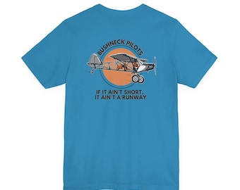 May include: A turquoise t-shirt featuring a graphic of a small airplane inside an orange circle. The text "Bushneck Pilots" arches above the plane, and below, the text reads "If it ain't short, it ain't a runway."