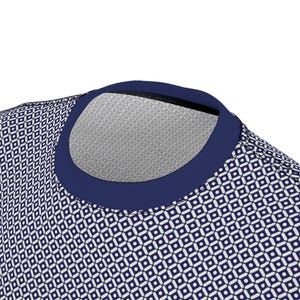 May include: A crew neck t-shirt featuring a repeating geometric pattern of small dark blue circles centered within white squares, all set against a dark blue background. The garment has a solid dark blue ribbed collar and visible stitching.
