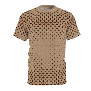 May include: A tan t-shirt featuring a repeating pattern of brown star-like shapes. The pattern density decreases from top to bottom. The shirt has a crew neck and short sleeves. The design is a geometric pattern.