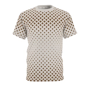 May include: A short-sleeved t-shirt featuring a repeating pattern of brown starburst shapes on a light grey background. The pattern density increases towards the bottom. The shirt has a crew neck and a relaxed fit.