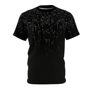 Puede incluir: Camiseta negra con un diseño de código binario. La parte superior de la camiseta presenta un patrón de dígitos binarios blancos que se desvanecen en el fondo negro. La camiseta de manga corta está hecha de un material suave.