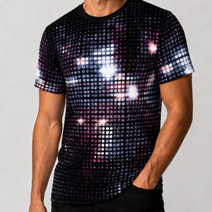 May include: A short-sleeved crew neck t-shirt featuring a black background with a repeating grid pattern of small squares in shades of purple, blue, and white, creating a reflective, light-catching effect across the front and sleeves.