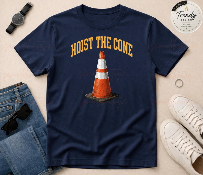 May include: Navy blue t-shirt featuring a graphic of an orange and white traffic cone on a black base. The text "HOIST THE CONE" is arched above the cone in yellow. A casual tee for everyday wear.