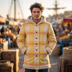 May include: A long-sleeved hooded coat featuring a yellow, white, and peach plaid pattern. The coat has a cream-colored faux shearling lining visible at the hood and cuffs, and it fastens down the center front with five dark brown buttons.