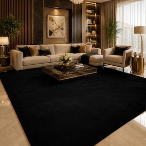 May include: A large, solid black area rug with a smooth, uniform texture covering the floor in a living room. The rectangular rug features clean, straight edges and a deep, dark colour that contrasts with the light-coloured marble flooring.