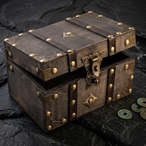 May include: A wooden treasure chest with a partially open lid. The chest is dark brown with brass accents, including corner brackets, studs, and a decorative clasp. Leather straps and a sunburst design add to the vintage aesthetic. A few antique coins are visible.
