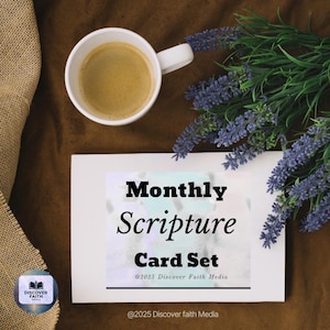 Puede incluir: Una taza de café blanca con café se encuentra cerca de un juego de tarjetas blancas con las palabras "Monthly Scripture Card Set". El juego de tarjetas está rodeado de flores moradas y un logotipo que dice "Discover Faith Media".