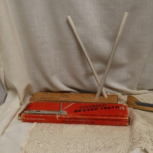 May include: An image of a vintage Colorado Beaver Teeth sharpening device. The red and orange box has text that reads "COLORADO BEAVER TEETH" and "THE BEST FRIEND A DULL EDGE EVER HAD". Two white sharpening rods are crossed.