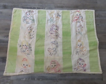 Puede incluir: Una colcha rectangular con paneles verticales alternos de tela verde claro sólido y blanca. Los paneles blancos están decorados con ilustraciones bordadas de niños interactuando con varios animales, incluyendo gatos, perros y pájaros.