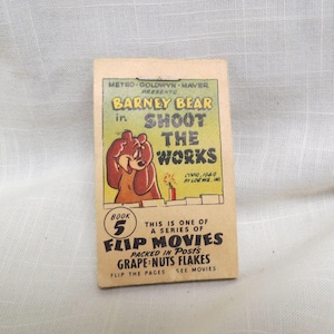 Peut inclure: Un livret vintage "Flip Movie" de Barney Bear, Livre 5, avec le titre "Shoot the Works". La couverture présente une illustration de dessin animé de Barney Bear et le texte "Packed in Posts Grape-Nuts Flakes."