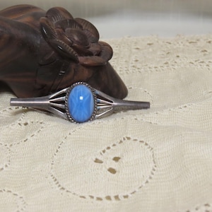 May include: A silver brooch with a blue oval cabochon stone set in a silver filigree design.
