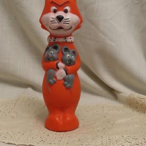 May include: Vintage orange plastic toy cat figure with a white face, black whiskers, and two gray mice on its chest. The cat has an angry expression and a white collar. A collectible toy.