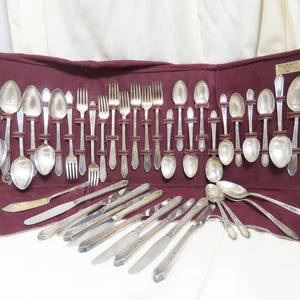 Peut inclure: Un ensemble d'argenterie vintage dans un étui en velours bordeaux. L'ensemble comprend des fourchettes, des cuillères et des couteaux, tous avec une finition argentée. L'étui porte une étiquette indiquant "Community Plate"