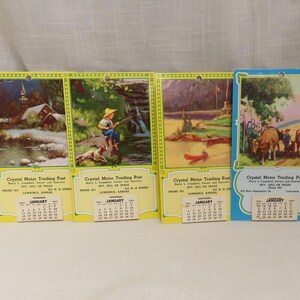 May include: Four vintage calendar cards with yellow borders and images of a cabin by a river, a boy fishing, a cabin in the woods, and a wagon train. Each card has a calendar for January and the text "Crystal Motor Trading Post" with contact information.