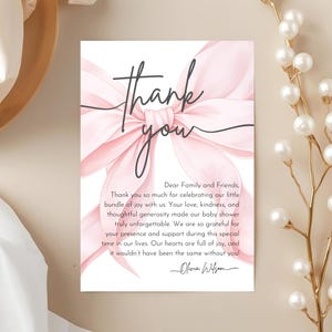 May include: A baby shower thank you card with a pink watercolor bow and the words "Thank You" in elegant script. The card includes a message of gratitude to family and friends.