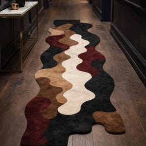 May include: A contemporary, abstract rug with a flowing design. The rug showcases a palette of black, brown, beige, and burgundy. It is placed on a wooden floor in a hallway. The rug is approximately 244 cm long.