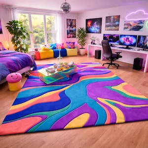 Puede incluir: Una habitación vibrante y colorida con una gran alfombra abstracta en tonos morado, azul, amarillo y naranja. La habitación cuenta con una cama con ropa de cama morada y azul, un escritorio con múltiples monitores y arte decorativo en las paredes. Una bola de discoteca cuelga del techo.
