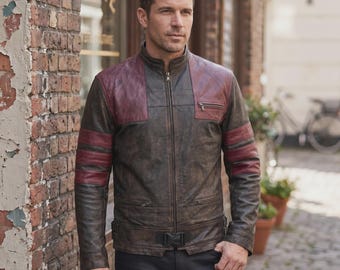 May include: A brown leather jacket with burgundy accents on the shoulders and sleeves. The jacket has a zip-up front, a small chest pocket, and a belt at the waist. The jacket is worn with black pants.