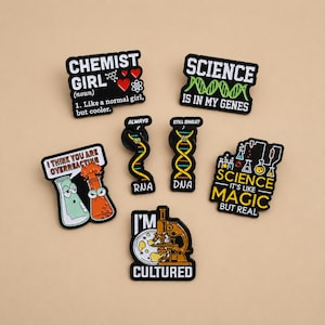 Peut inclure: Un ensemble de six pin's en émail sur le thème de la science, incluant un microscope avec le texte I'M CULTURED, des brins d'ADN et d'ARN, des béchers de laboratoire et des phrases comme CHEMIST GIRL, SCIENCE IS IN MY GENES et SCIENCE IT'S LIKE MAGIC BUT REAL.