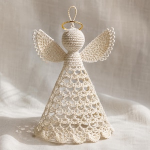 May include: A cream-colored crocheted angel ornament featuring a spherical head, outstretched wings with scalloped edges, and a conical skirt with an openwork lace pattern. A thin gold-colored wire halo sits atop the head with a small loop.