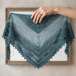 May include: A triangular knitted shawl in a gradient of teal and blue-green hues. The accessory features a delicate lace pattern throughout the body and a decorative picot edge along the bottom border, showcasing intricate yarn work and texture.