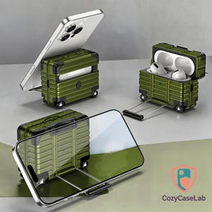 Peut inclure: Étuis de téléphone et d'AirPods vert olive en forme de valise. L'étui de téléphone contient un téléphone argenté, et l'étui d'AirPods est ouvert, révélant des écouteurs blancs. Chaque étui a de petites roues et une poignée.