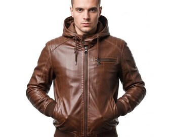 May include: Brown leather jacket with a hood, zipper closure, and ribbed cuffs and hem. The jacket has a small zippered pocket on the chest and two front pockets. The jacket is worn by a person against a white background.