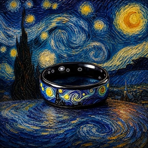 May include: A black band ring featuring a detailed wrap-around print of a swirling night sky with a bright yellow crescent moon, glowing stars, and dark cypress tree silhouettes, mirroring the iconic post-impressionist painting style.