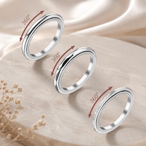 Peut inclure: Trois bagues argentées disposées en diagonale. La bague supérieure est lisse et unie. La bague centrale présente une surface facettée et texturée. La bague inférieure est incrustée de petites pierres claires. Chaque bague a une flèche rouge.